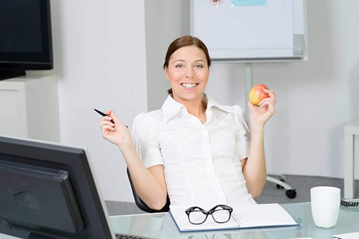 mujer en oficina comiendo una manzana