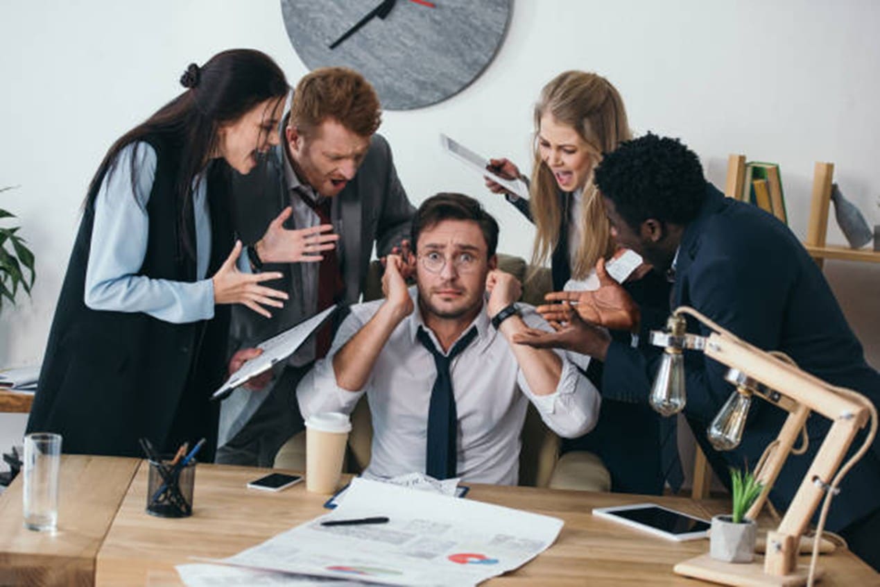 personas gritando a un hombre en oficina