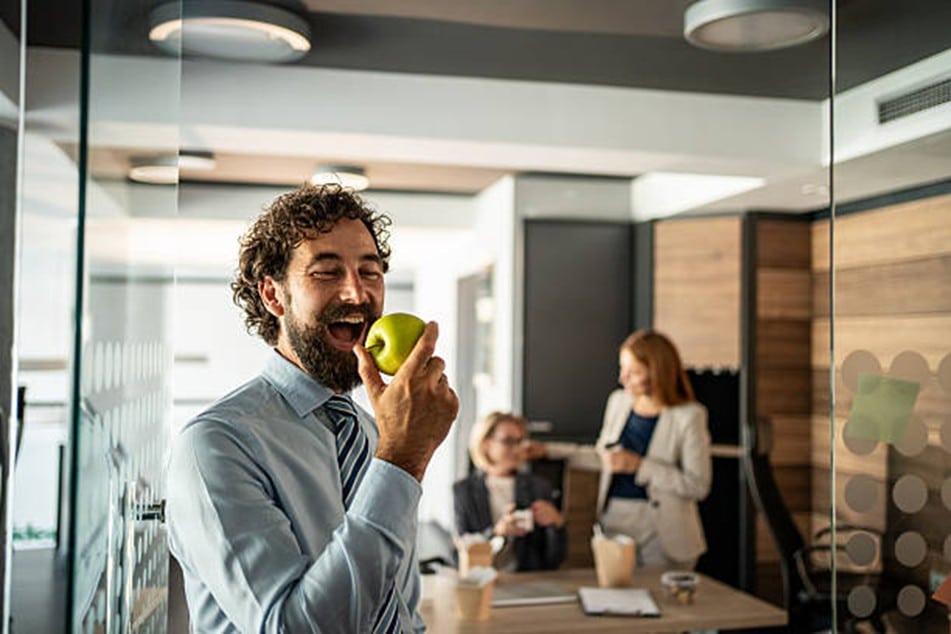 hombre sonriendo comiendo una manzana